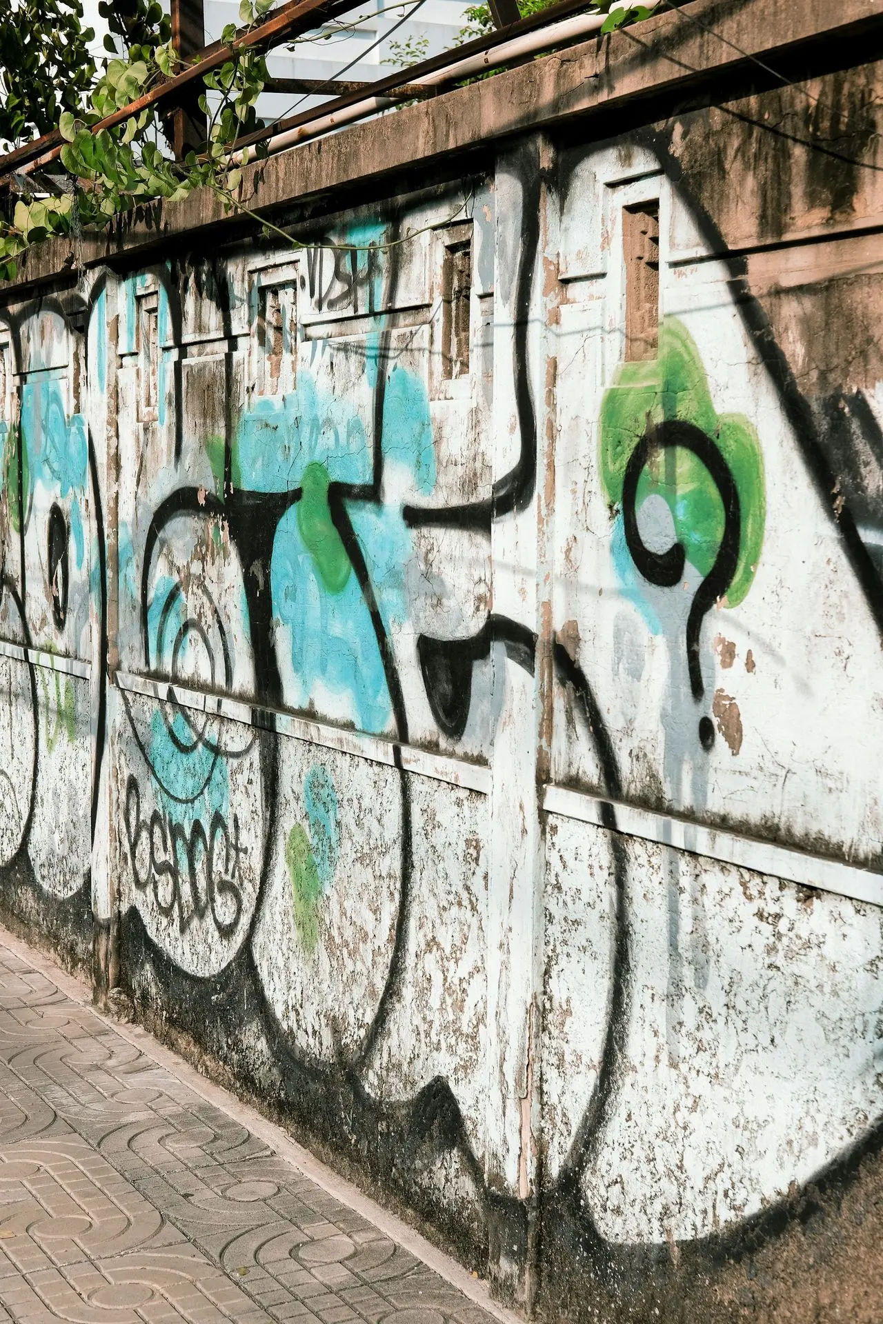 A man riding a skateboard past a graffiti covered wall